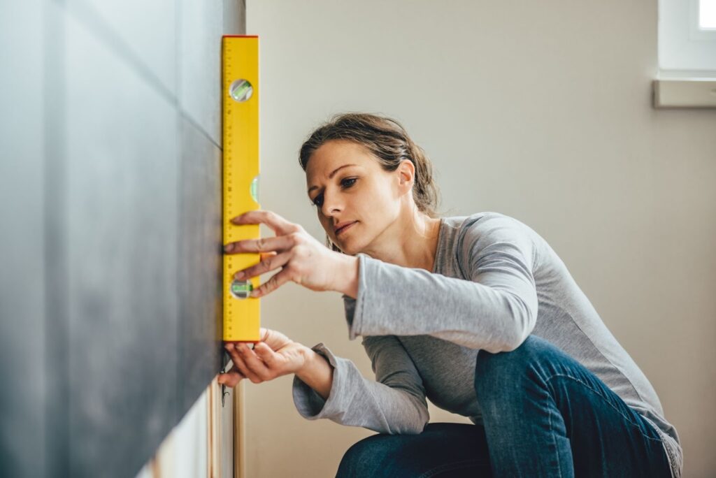 a woman using a spirit level on the wall