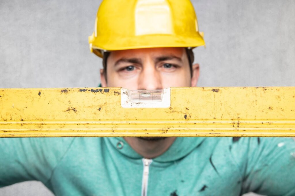 A man in a yellow hard hat with a spirit level 