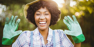 Happy,Woman,Showing,Her,Gardening,Gloves,In,The,Garden
