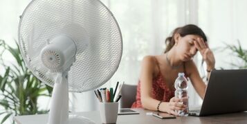 Woman,Sitting,At,Desk,At,Home,During,A,Summer,Heat