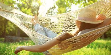 Young,Woman,With,Hat,Resting,In,Comfortable,Hammock,At,Green